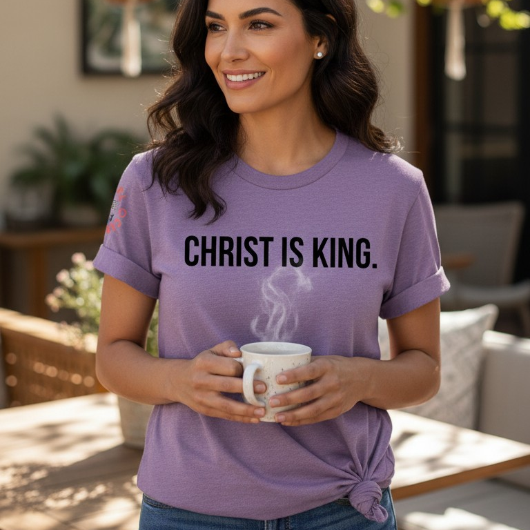 Woman wearing a purple 'Christ is King' t-shirt holding a mug outdoors.